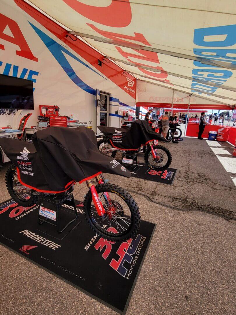 Motorbikes covered in racing team tent.