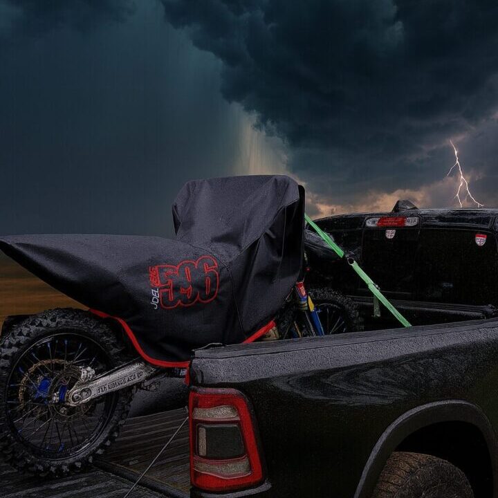 A motorcycle loaded on a truck bed under stormy skies with lightning.